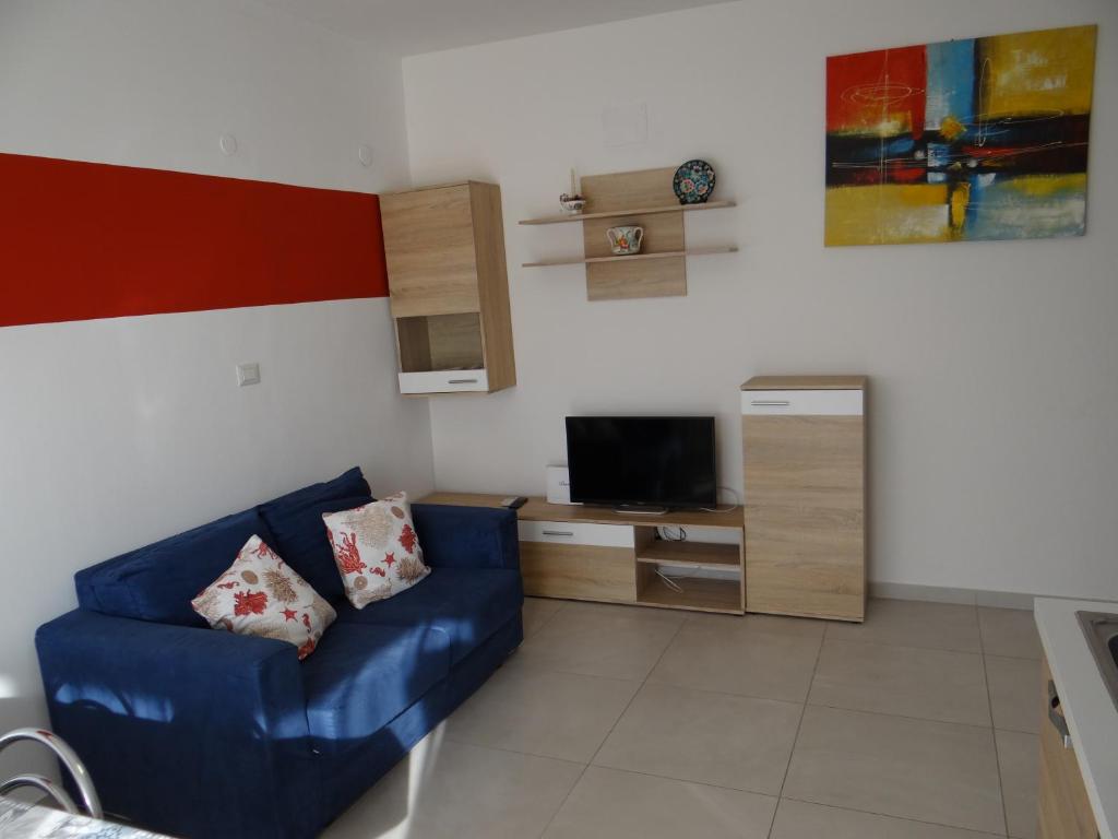 ein Wohnzimmer mit einem blauen Sofa und einem TV in der Unterkunft Luminoso Appartamento al mare in Martinsicuro