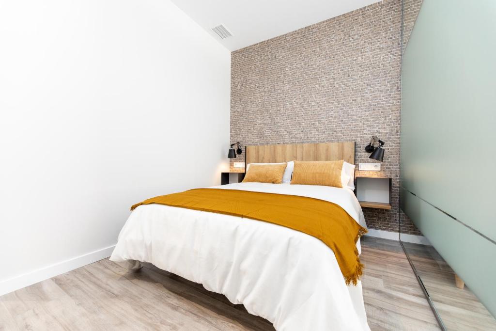 um quarto com uma cama grande e uma parede de tijolos em APARTAMENTOS AVENIDA DE AMERICA em Toledo