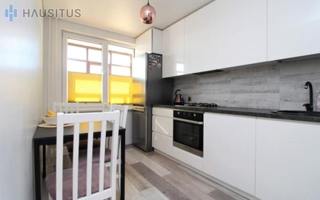 a kitchen with white cabinets and a sink and a stove at Nemuno apartamentai in Panevėžys