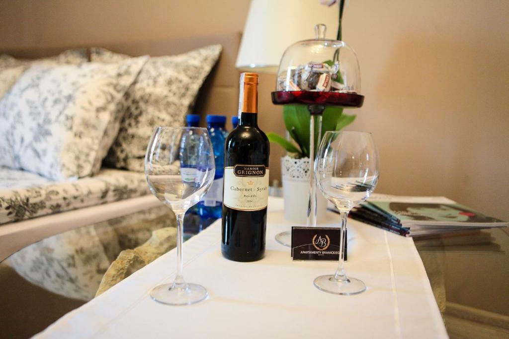 a bottle of wine and two wine glasses on a table at Branicki Apartments in Białystok