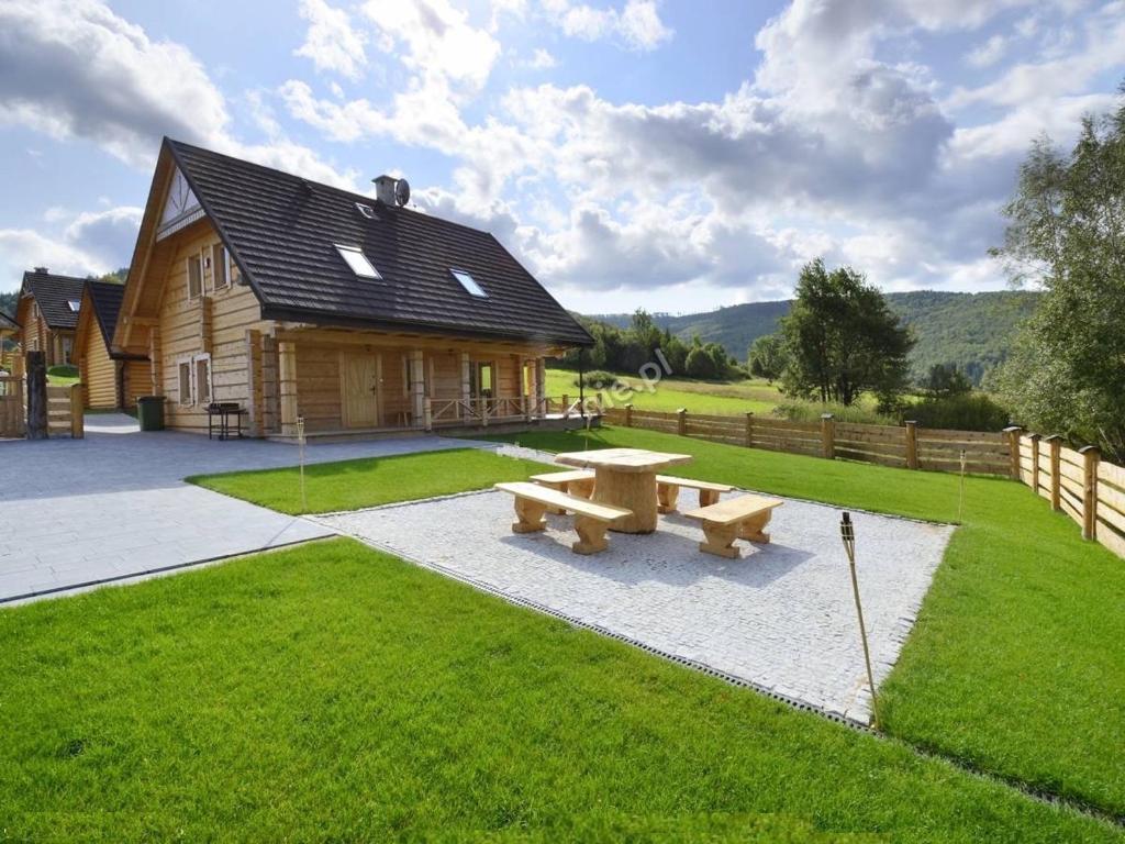 una mesa de picnic frente a una cabaña de madera en Domki Zawoja z Jacuzzi, en Zawoja