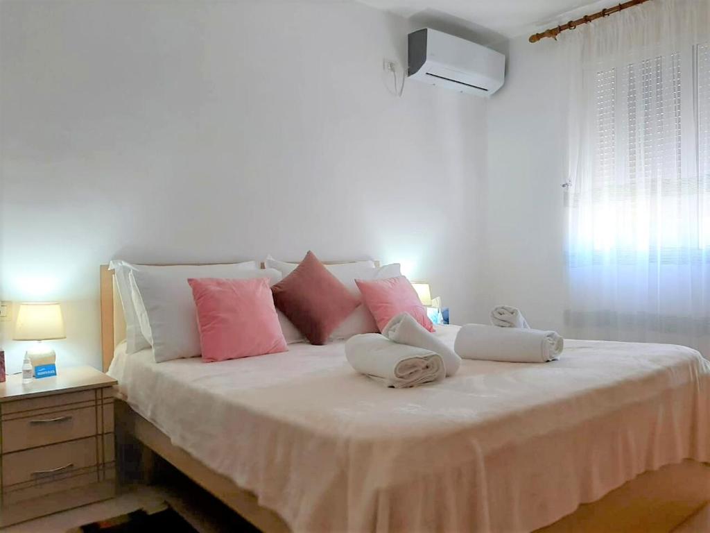 1 dormitorio con 1 cama grande con almohadas rosas y blancas en Sazani's Place, en Fier