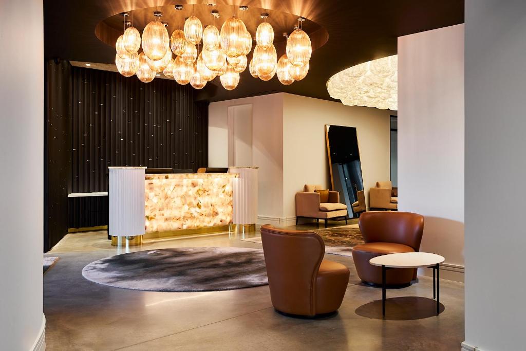 a lobby with chairs and a table and chandeliers at Astina Suites, Penrith in Penrith