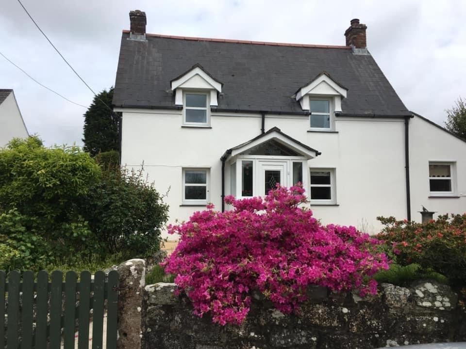 a white house with pink flowers in front of it at Rose Cottage room Bee Happy in Newquay