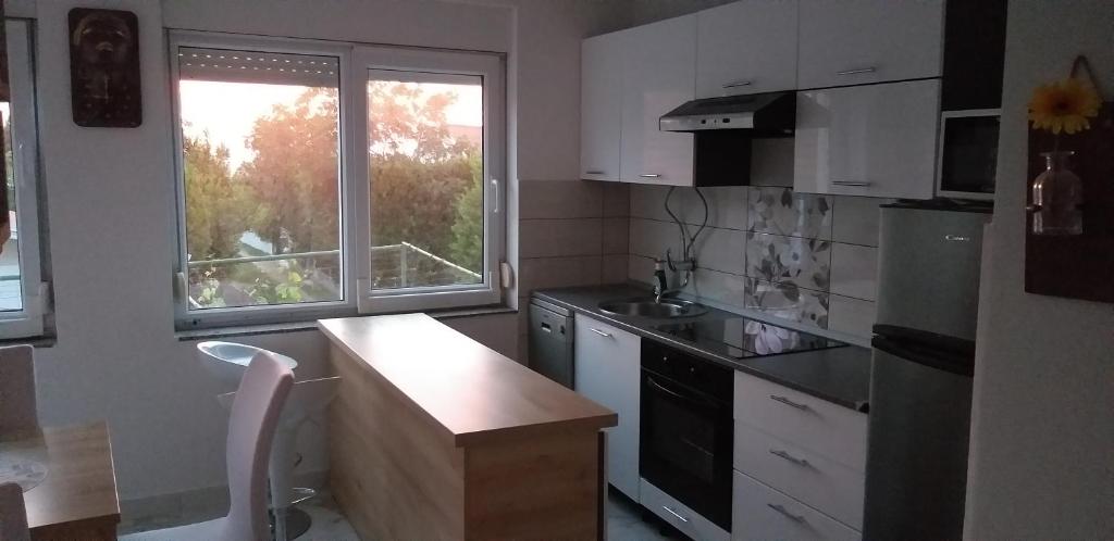 kuchnia z blatem, umywalką i oknem w obiekcie Apartman Zvončica w mieście Vrsi