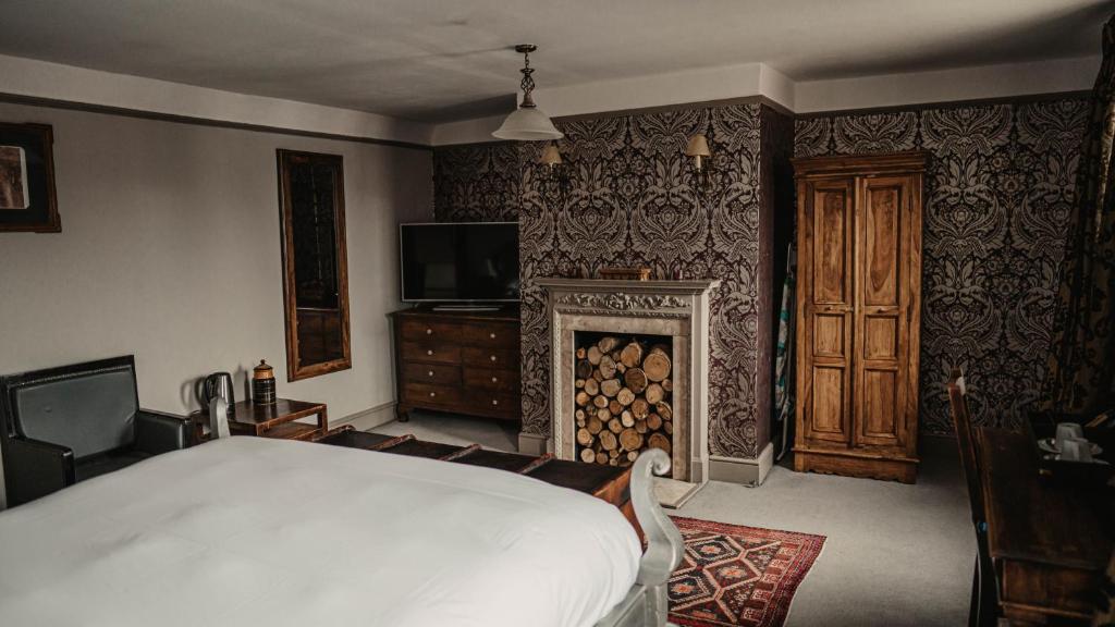 a bedroom with a large bed and a fireplace at Elephant Hotel in Pangbourne