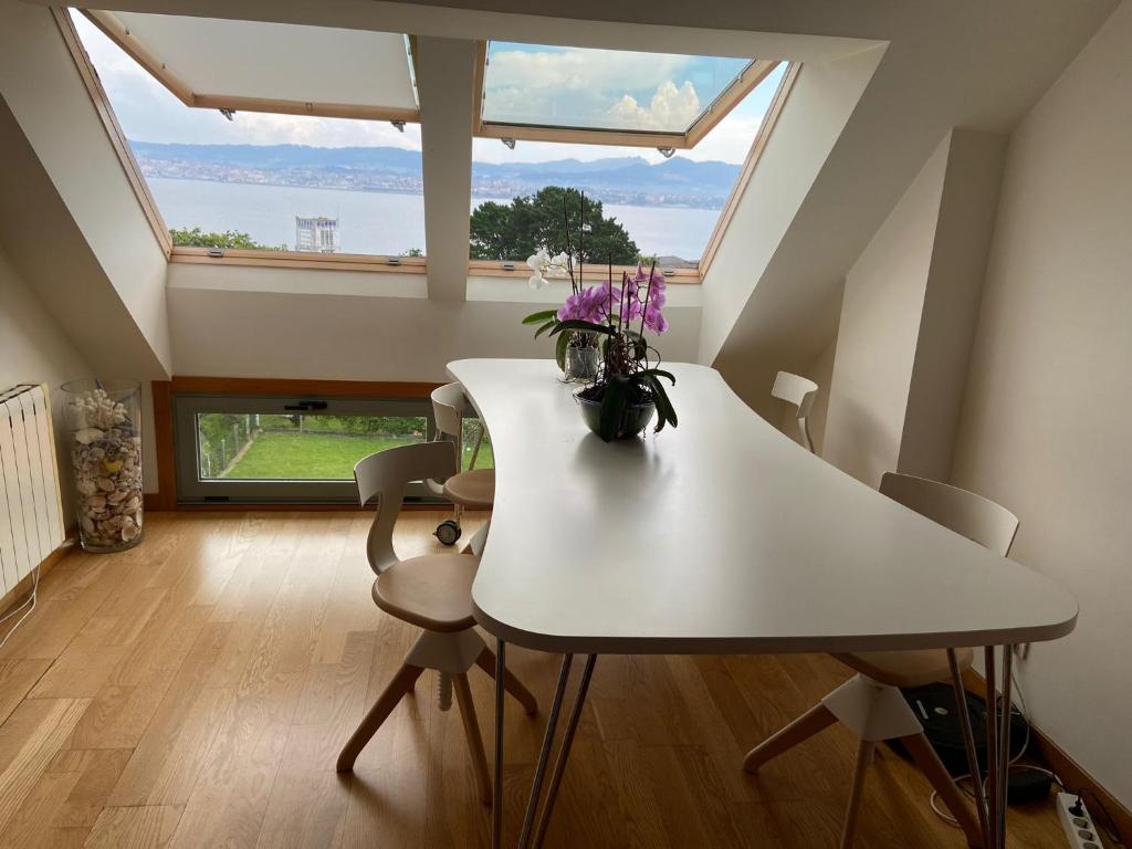 una mesa y sillas blancas en una habitación con una ventana grande en Ático Masso, en Cangas de Morrazo