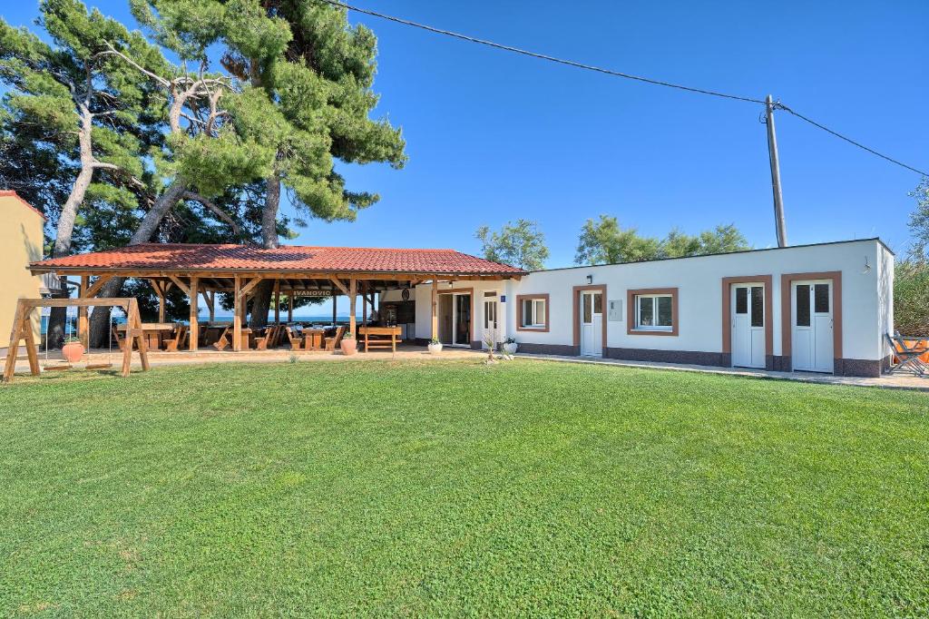 un edificio con un campo de césped delante de él en Apartments & Bungalows Ivanović, en Kaštela