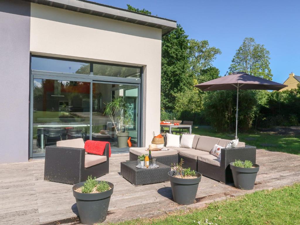 eine Terrasse mit 2 Sofas und einem Sonnenschirm in der Unterkunft Holiday Home Penn Sardin - DNZ100 by Interhome in Douarnenez