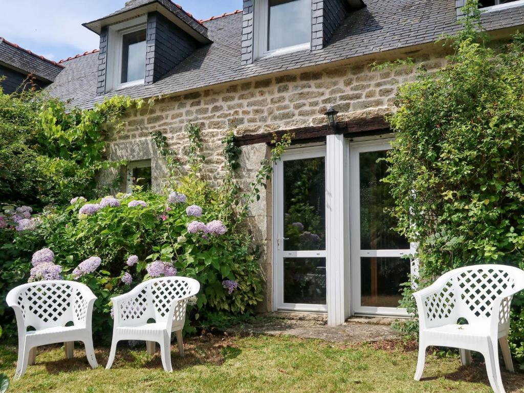 drei weiße Stühle vor einem Haus mit Blumen in der Unterkunft Holiday Home La Ferme Bis by Interhome in Loctudy