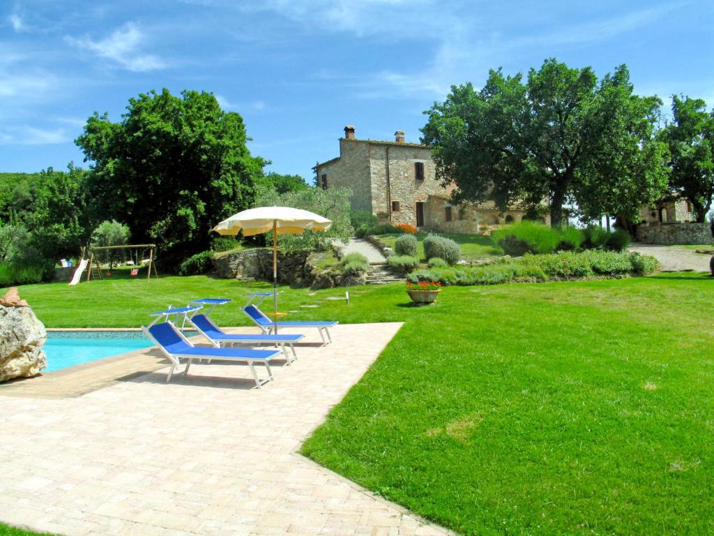 a pool with two blue chairs and an umbrella at Apartment San Lorenzo-2 by Interhome in La Cava