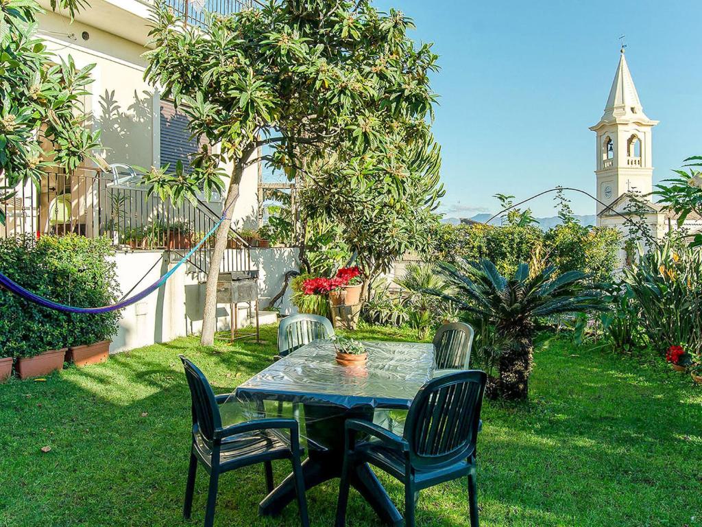 a table and chairs in a yard with a clock tower at Apartment Etna View by Interhome in Mascali