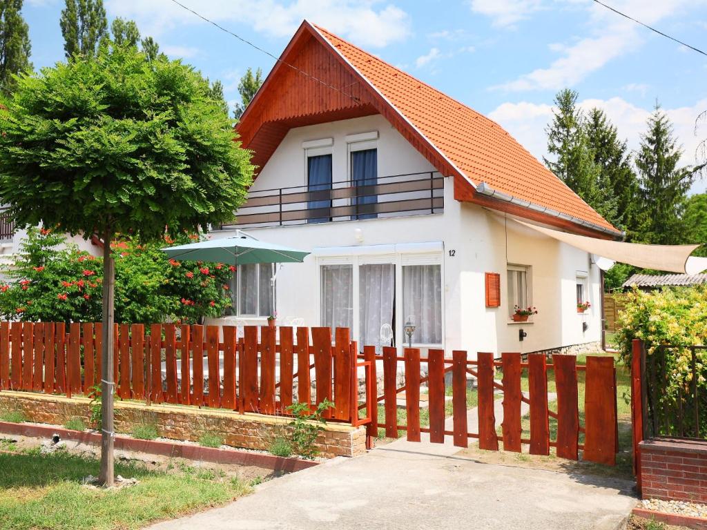 una casa blanca con techo naranja y valla en Holiday Home Margaret by Interhome, en Balatonfenyves