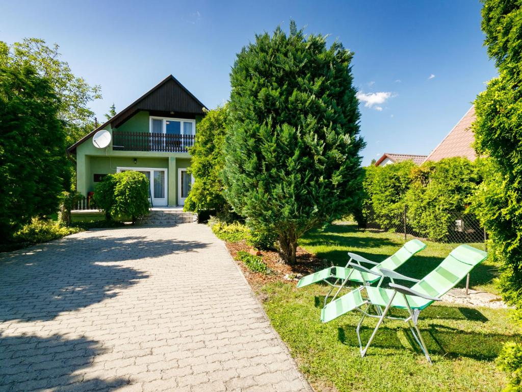 a pair of green chairs sitting on the grass in front of a house at Holiday Home Verde by Interhome in Balatonlelle
