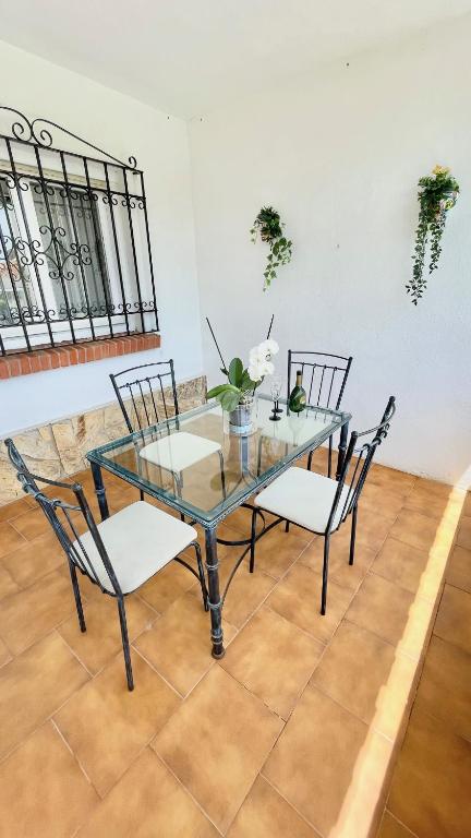 szklany stół z 2 krzesłami i stół z kwiatami w obiekcie Chalet en primera Línea con 150m2 de Jardín Privado w mieście Torrox Costa