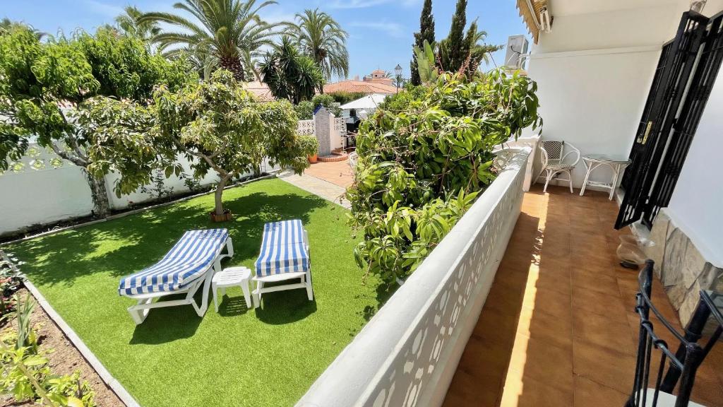 balkon z 2 krzesłami i trawnikiem w obiekcie Chalet en primera Línea con 150m2 de Jardín Privado w mieście Torrox Costa
