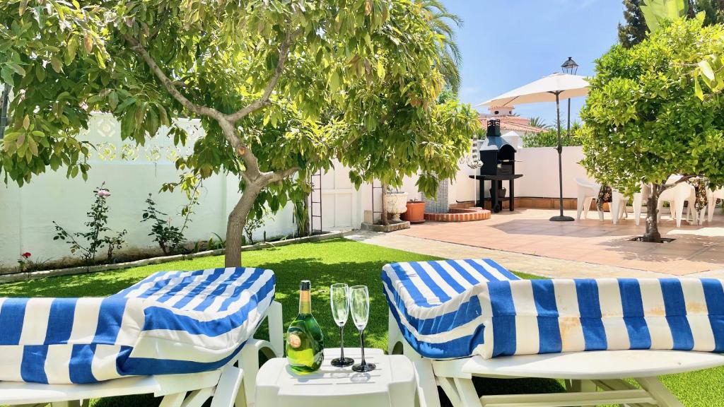 dwa krzesła i stół z kieliszkami i butelkami wina w obiekcie Chalet en primera Línea con 150m2 de Jardín Privado w mieście Torrox Costa