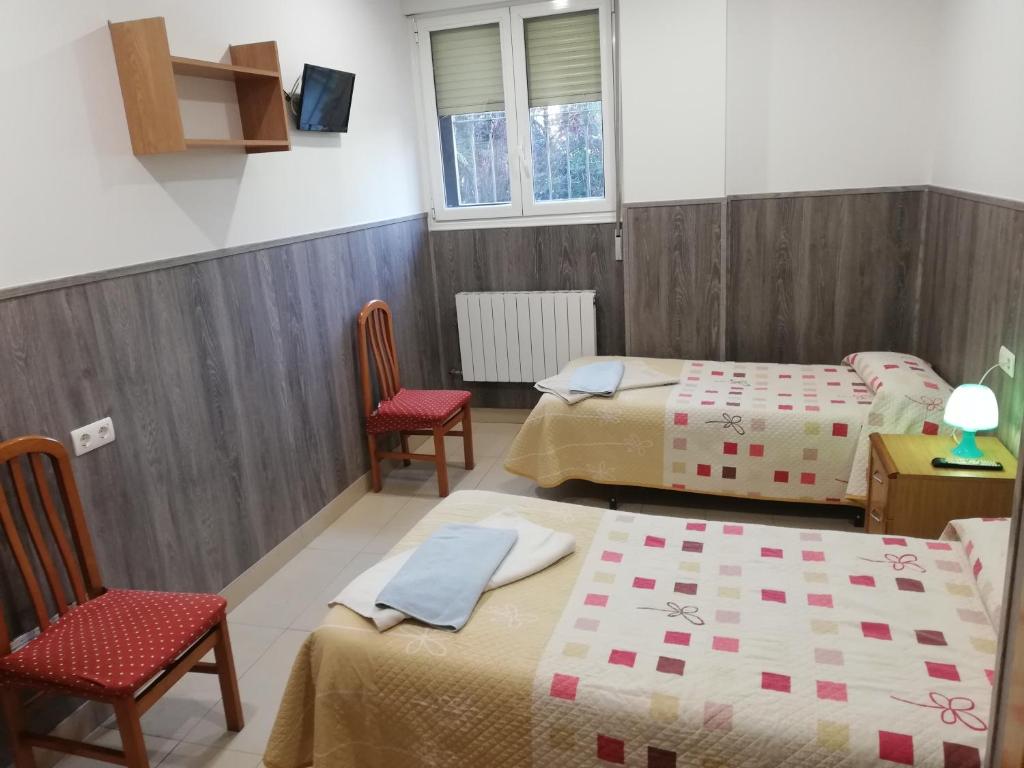 - une chambre avec deux lits et deux chaises dans l'établissement Pensión Agarimo, à Trapagaran