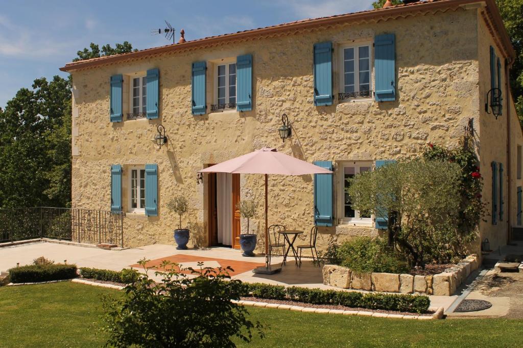 a stone house with an umbrella in front of it at Maison d'Hôtes Las Baillargues de Haut in Mouchan