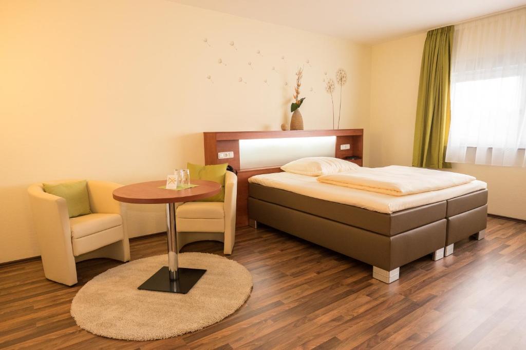 a bedroom with a bed and a table and a chair at Hotel Viola in Hochheim am Main