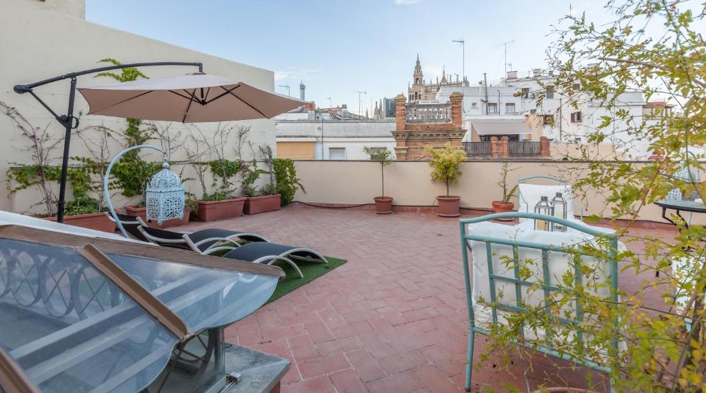 a patio with an umbrella and chairs on a roof at Roof Cathedral Sevilla in Seville