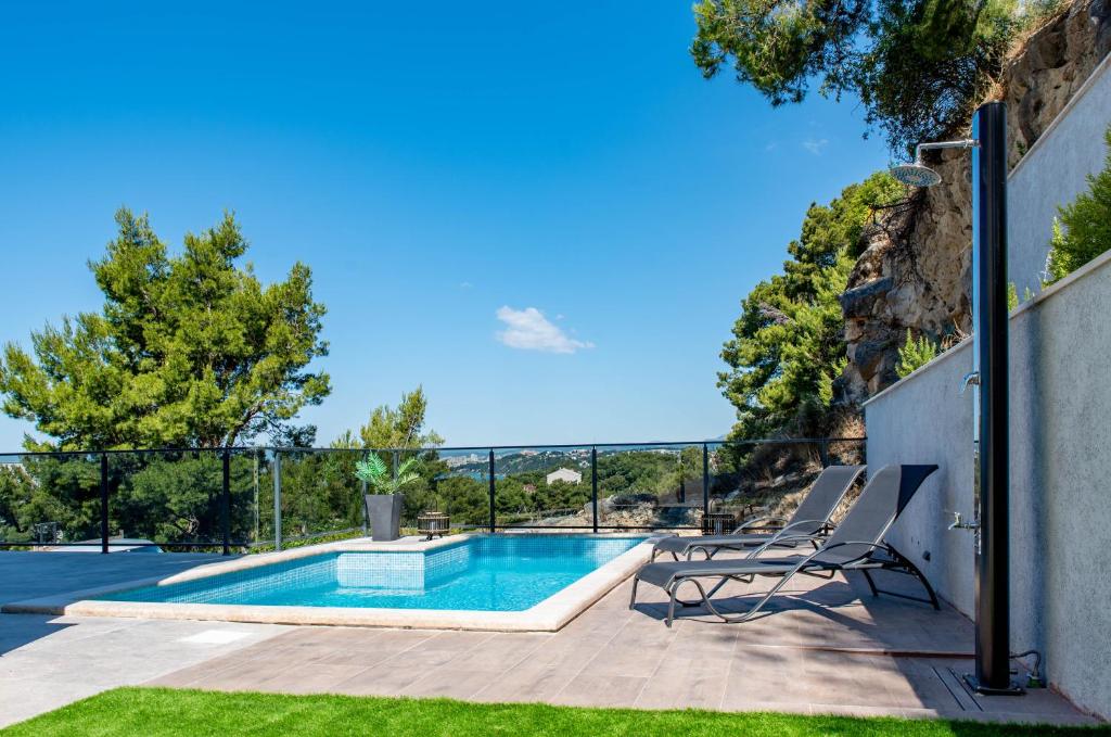 a patio with a pool and two chairs next to a fence at Lion's Beach Apartment in Podstrana