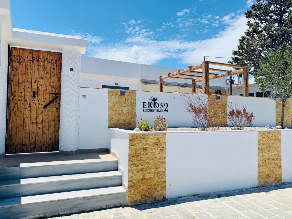a white building with a wooden door and stairs at EROS LUX VILLE 2 in Faliraki