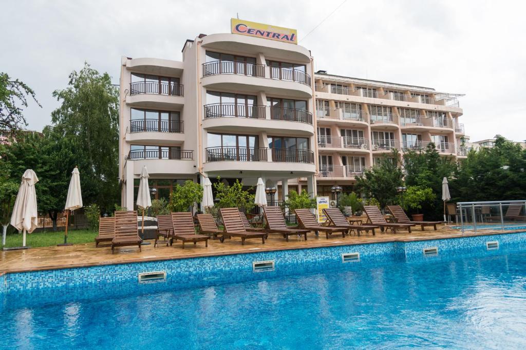 um hotel com uma piscina com cadeiras e guarda-sóis em Hotel Central em Sunny Beach