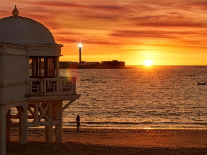 a person standing on a beach with a lighthouse at Cádiz caleta modulo in Cádiz