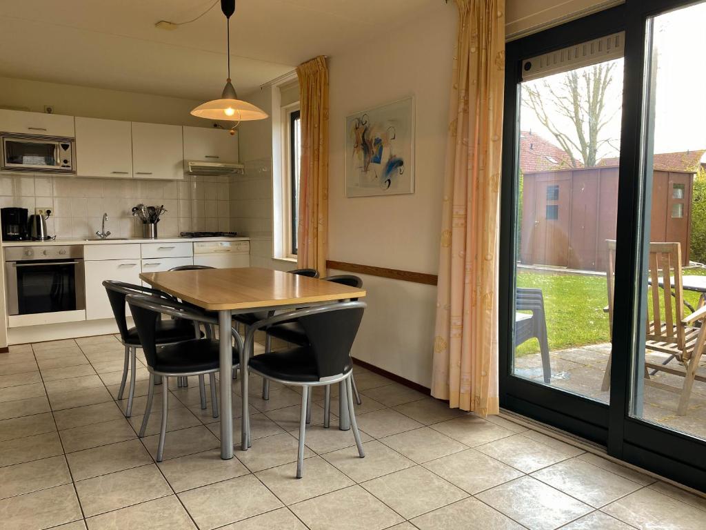 uma cozinha com uma mesa de madeira e cadeiras pretas em Hello Zeeland - Vakantiehuis Stern 265 em Breskens