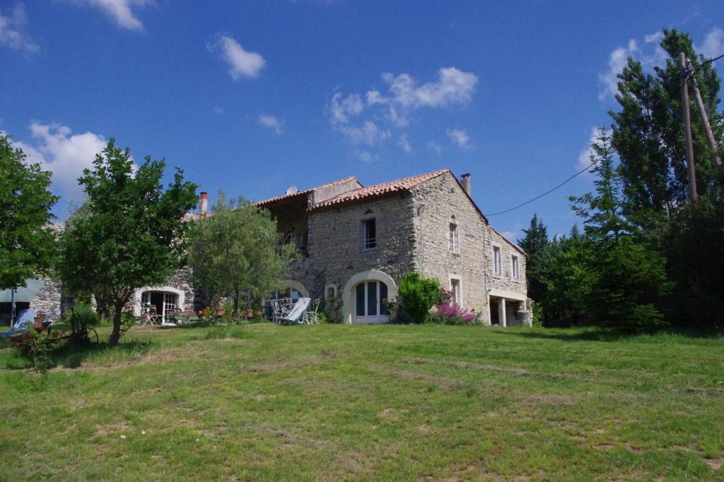 une grande maison en pierre sur un champ herbeux dans l'établissement Chambres d'Hotes La Grange au Negre, à Alba La Romaine