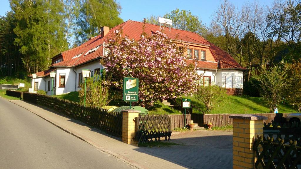 uma casa com uma cerca e uma árvore com flores cor-de-rosa em Hotelpension Schwalbennest em Benz