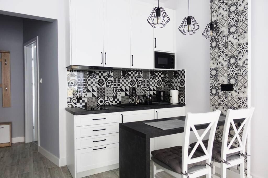 a kitchen with white cabinets and black and white tiles at Apartament Warsaw Old Town - Piwna Street in Warsaw