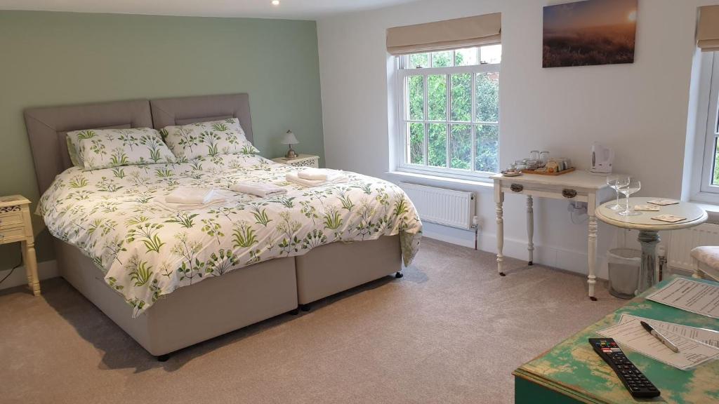 a bedroom with a bed and a table and window at Argyll House Bed and Breakfast in Westleton