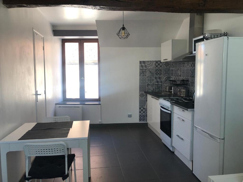 a kitchen with a table and a white refrigerator at Studio centre historique Sancerre in Sancerre