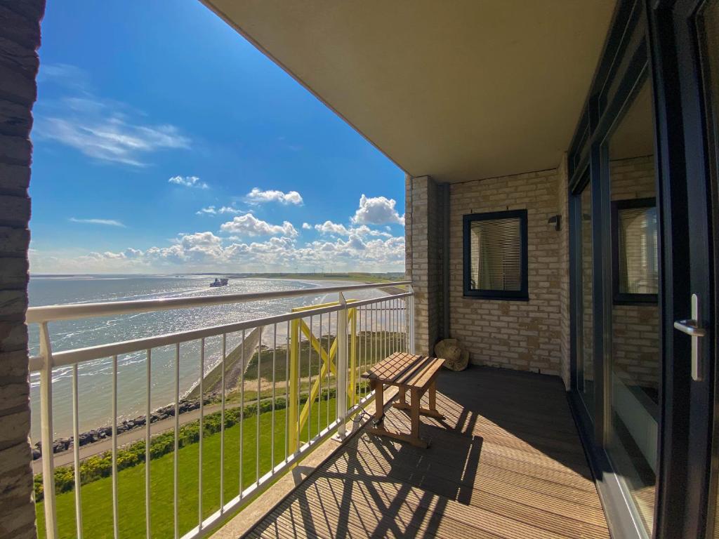 a balcony with a bench and a view of the beach at Hello Zeeland - Appartement Port Scaldis 21-072 in Breskens