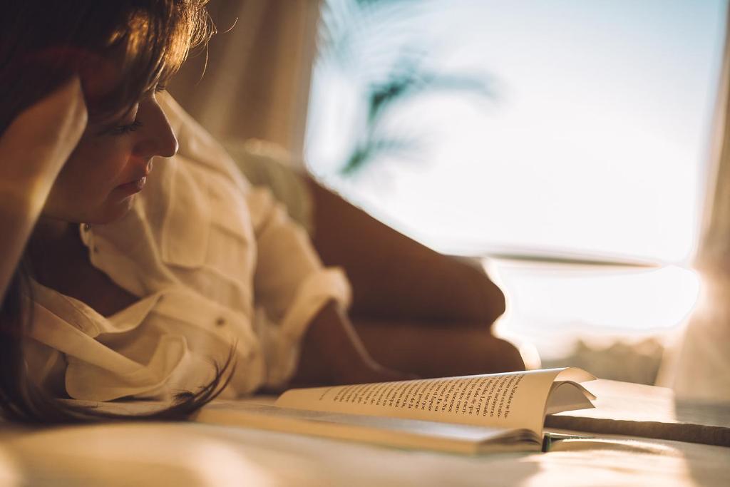 a woman laying on a couch reading a book at Las Gaviotas Suites Hotel & Spa in Playa de Muro
