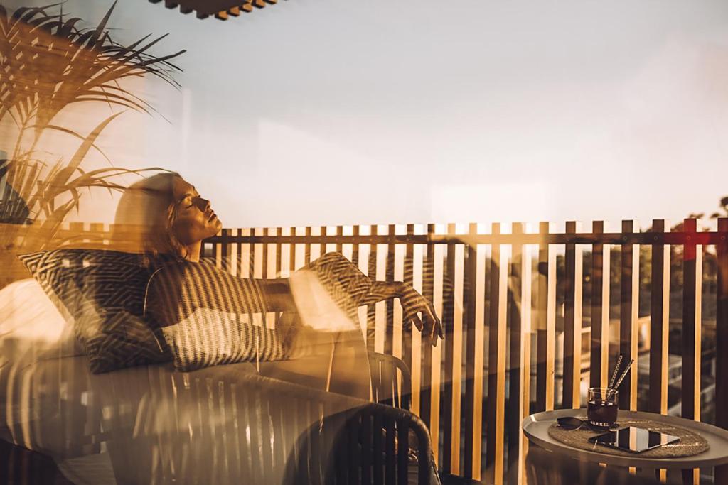 a man sitting on a couch next to a fence at Las Gaviotas Suites Hotel & Spa in Playa de Muro