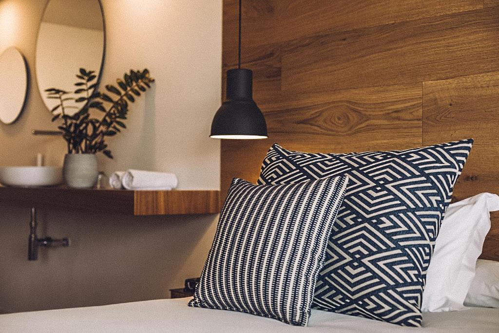 a bed with a black and white pillow and a mirror at Las Gaviotas Suites Hotel & Spa in Playa de Muro