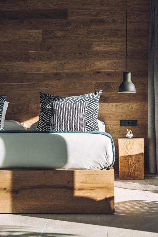 a bedroom with a bed with a wooden wall at Las Gaviotas Suites Hotel & Spa in Playa de Muro