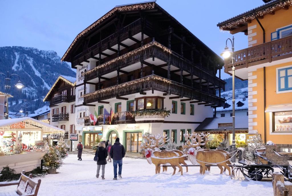 un gruppo di persone che camminano sulla neve di fronte a un edificio di Post Hotel Ristorante Tyrol a Moena