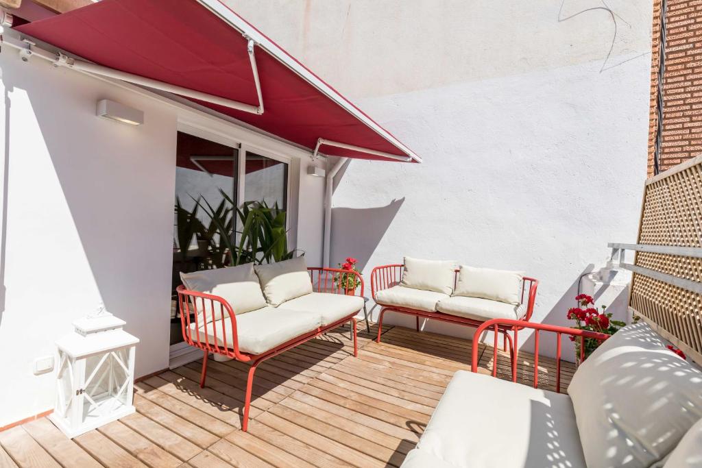 a patio with two chairs and a red awning at Maison Reina in Valencia