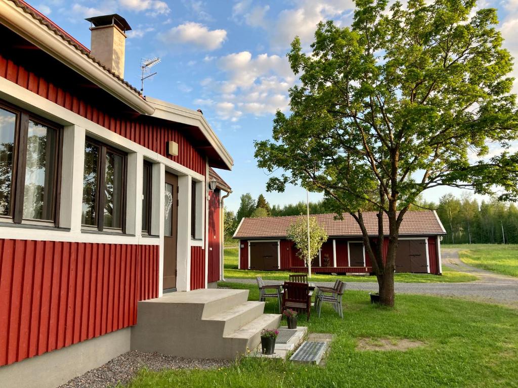 a red building with a picnic table and a tree at Villa Taikinajoki in Pertunmaa