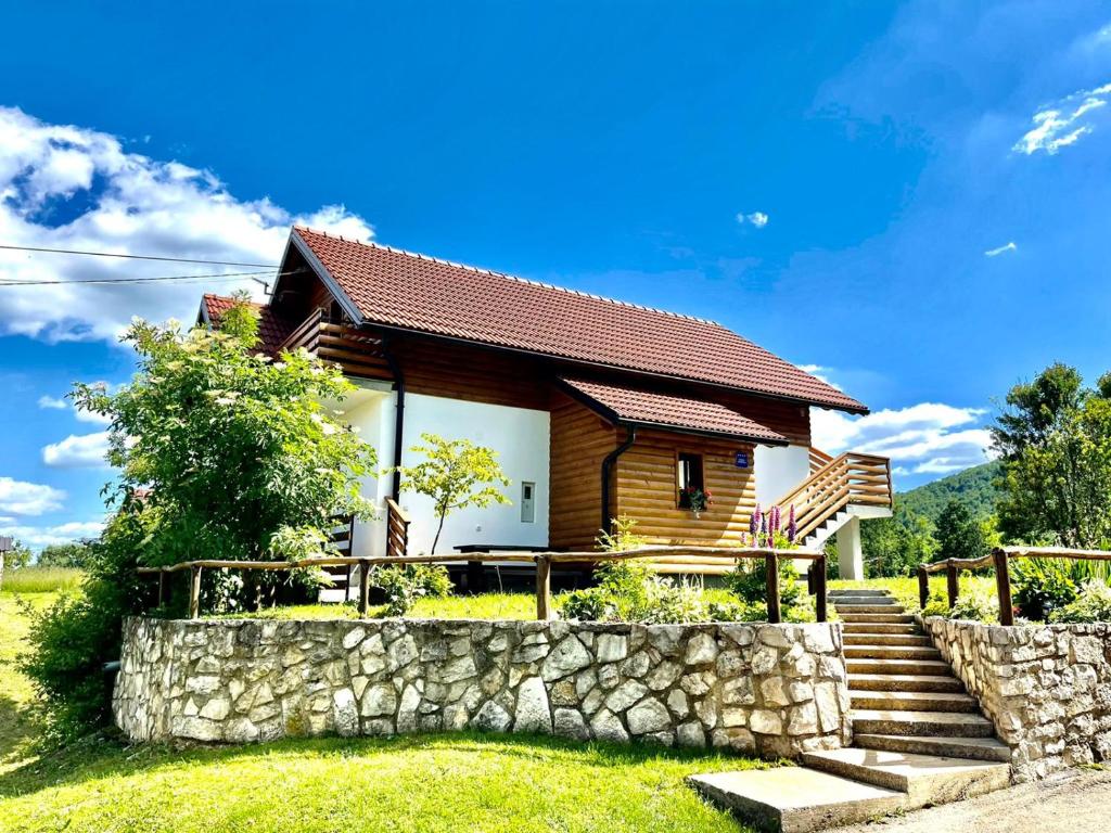 a house with a stone fence and a stone wall at Studio Apartmani Patricia in Smoljanac