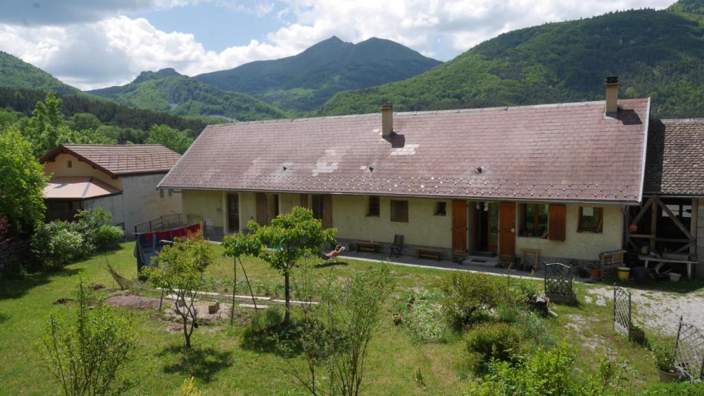 une maison au milieu d'un champ avec des montagnes dans l'établissement Chambres et table d'hôte Le Petit Radis, à Lus-la-Croix-Haute