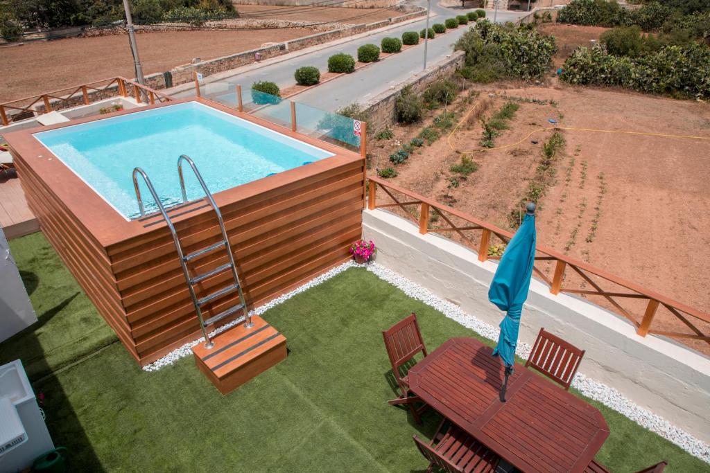 an overhead view of a swimming pool with two chairs and a umbrella at Tal-Karmnu Entire house with private heated pool and jacuzzi in Kirkop