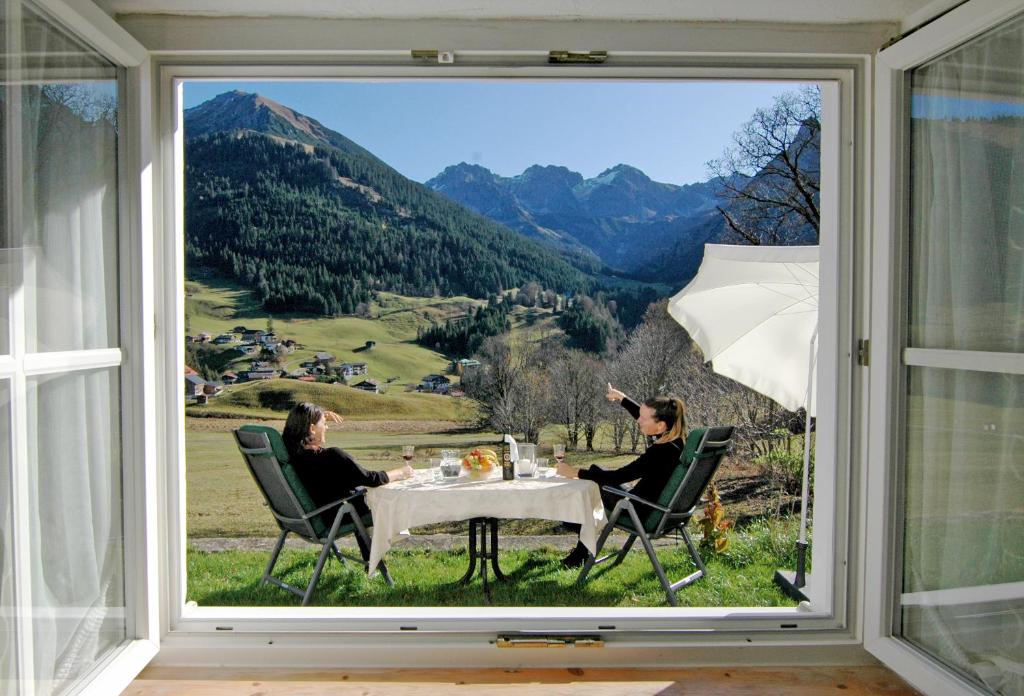 duas mulheres sentadas numa mesa a olhar pela janela em Ferienhaus Ahorn em Mittelberg