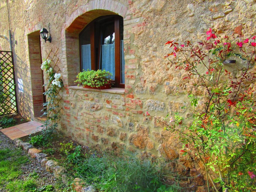 un edificio de ladrillo con una ventana con flores. en Il Mandorlo di Monteriggioni en Monteriggioni