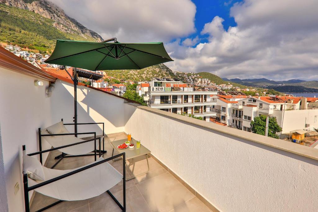 een balkon met een groene parasol en stoelen bij Joyy Suit Apart in Kas