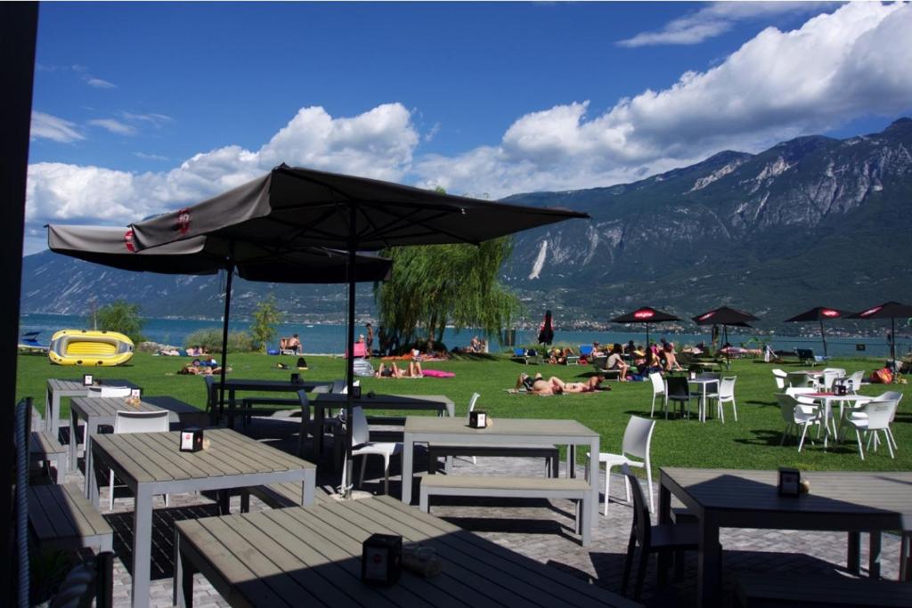 a group of tables and chairs with people on the grass at Campione Univela Hostel in Campione del Garda